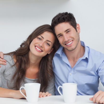 Couple embracing each other in the kitchen with a cup of coffee