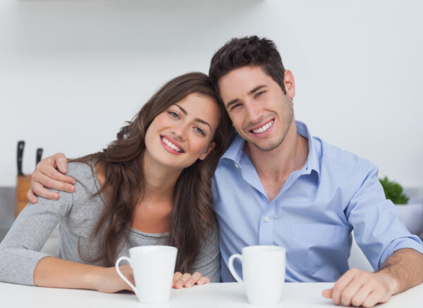 Couple embracing each other in the kitchen with a cup of coffee