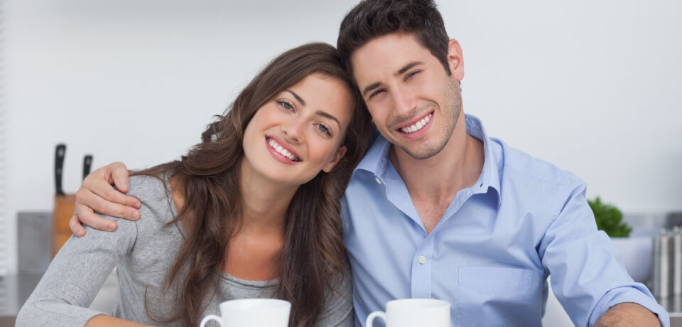 Couple embracing each other in the kitchen with a cup of coffee