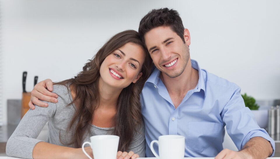 Couple embracing each other in the kitchen with a cup of coffee