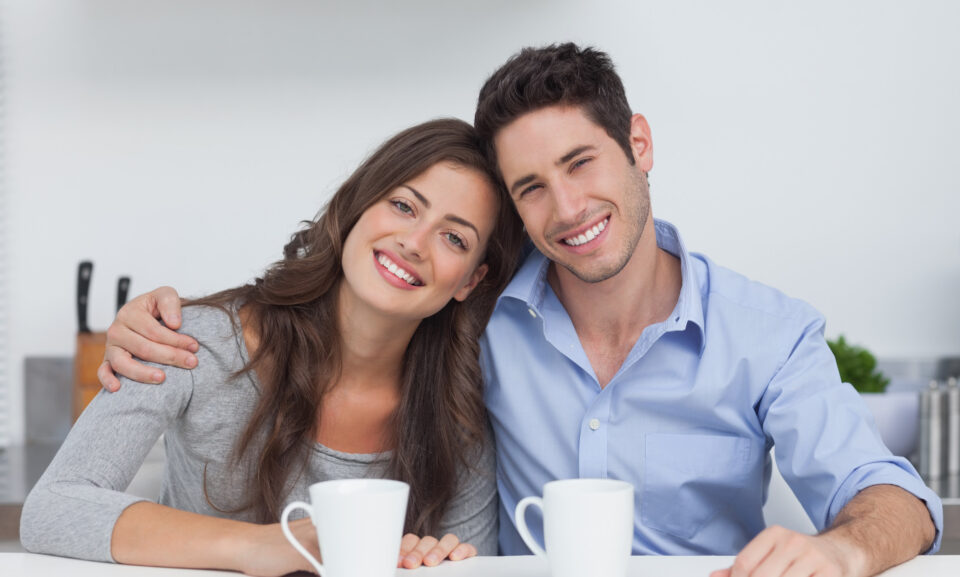Couple embracing each other in the kitchen with a cup of coffee
