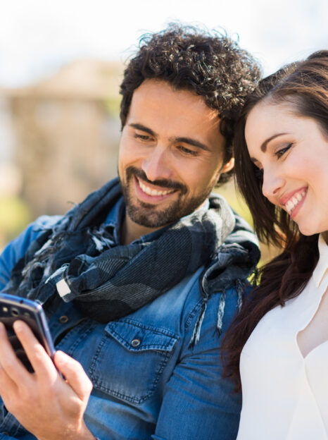 Smiling man showing his mobile phone to a girl