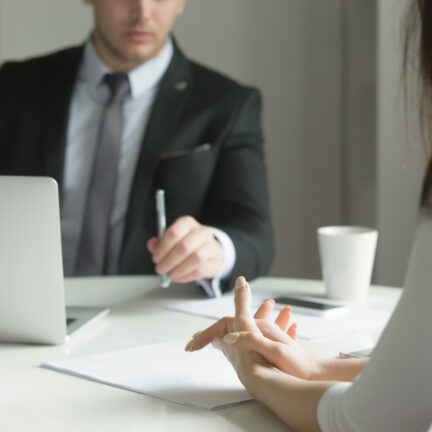 Close up of business people hands hold at an office desk, young man and woman are having a business talk. The woman feels stressed. Business concept photo
