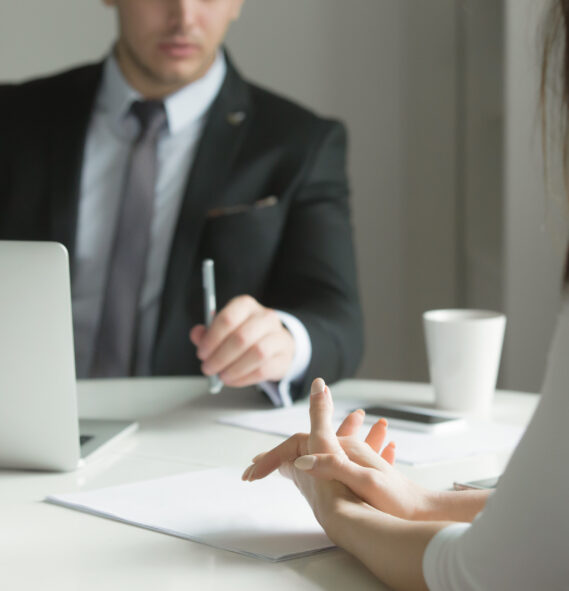 Close up of business people hands hold at an office desk, young man and woman are having a business talk. The woman feels stressed. Business concept photo